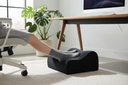 Person resting feet on memory foam foot rest pad under desk