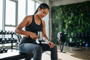 Athlete using percussion massage gun on thigh after workout