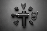 Percussion massage gun full kit flat lay with attachments and charging cable